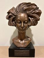 Front view of bronze-like female bust sculpture showing detailed facial features and voluminous hair.