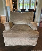 Front view of beige chenille lounge chair showing seat cushion, back pillow, rolled arms and floor-length skirt.