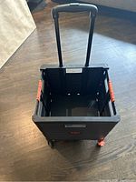 Open view of the black folding storage bin showing interior and telescoping handle extended