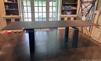 Front view of table fully extended showing black glass top and metal base legs
