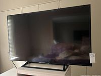 Front view of TV on stand atop dresser with screen off