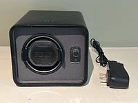 Front view of the watch winder showing BIRKS branded watch holder and AC adapter next to it.