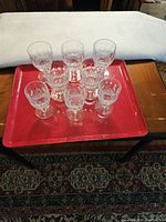 Front view of all 8 Waterford Colleen pattern drinking glasses arranged on a red tray.