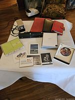 Photo showing full assortment of stationery and office supplies on a white cloth-covered surface, laid out clearly.