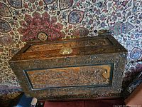 Closed chest top view on patterned rug showing overall shape and carved panels
