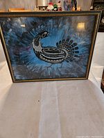 Framed print showing a stylized bird on a blue and black abstract background.