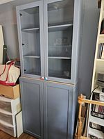 Front full view of two-piece cabinet unit showing glass top doors and solid bottom doors with colorful knobs.