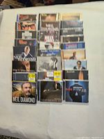 Photo shows 25 CD jewel cases laid out on a white surface, featuring well-known crooners such as Neil Diamond, Billy Joel, and others.