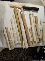 Top view showing multiple rolled needlepoint canvases arranged on a white surface with varied neutral colors and counts.