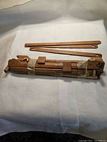 Top view of compact wooden table loom with two wooden shuttles on a white cloth background.