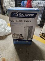 Photo of the Garrison oil-filled heater box showing brand, wattage settings, and heater image.