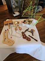 Overview of knitting paraphernalia including wooden tools, green yarn swift, and small yarn accessories arranged on white cloth.