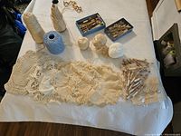 Wide layout showing wooden bobbins, various threads on cones and balls, and five lace doilies spread flat.