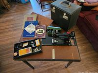 Overall lot on folding table showing machine, case, manuals, trays