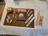 Full set of needlepoint tools and pom poms arranged on a brown mat showing all variety of items