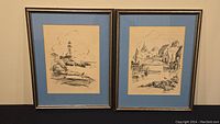 Two charcoal prints framed, matted with blue mats, depicting coastal scenes by de Garthe.