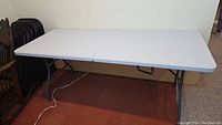 Full view of the white folding table opened with metal legs extended.