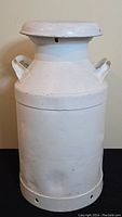 Front view of the vintage white metal milk can with lid