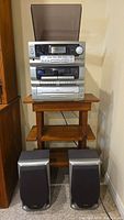 Full view of TEAC stereo system stacked on a small wooden stand with pair of stereo speakers placed on floor in front