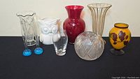 Full group of seven decorative pieces including glass vases, ceramic owl, and rose bowl on black surface