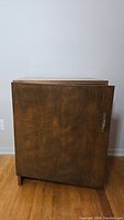 Front view of a vintage wooden cabinet with a closed door and a rectangular shape.