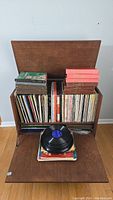 Wide view of wooden cabinet filled with vinyl records, some boxed sets on top and stacks of records.