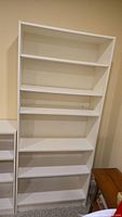 Full front view of white wooden bookcase, displaying all five shelves.