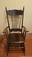 Full view of the antique wooden rocking chair showing carved press back, armrests and seat