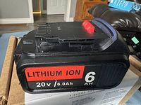 Side view showing 20V 6.0Ah Lithium Ion battery rating on red and black label with release button.