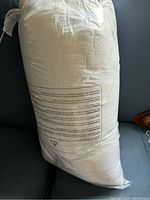 View of pillow in plastic packaging with caution care label.