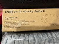Photo showing box details with product specifications and instructions about body heating pad temperature levels and washability.
