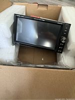 Front view of the Boss Audio car stereo in the original packaging showing the touchscreen and side control buttons.