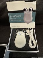 Facial toning device in original box with USB cable and instruction manual visible