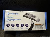 Box of Etekcity Digital Luggage Scale EL11 showing product name and key features including auto-off, overload indicator, low battery indicator, temperature sensor, and accurate sensors.