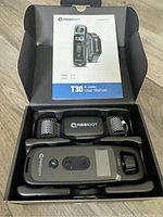 Opened box showing T30 e-collar and remote in black with manual on top