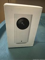 Front of the product box showing image of the white camera with a large black lens.