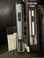 Ovente electric wine opener in stainless steel and clear plastic with instruction manual and original packaging box showing the product.