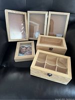 Six wooden craft and shadow boxes arranged on black surface showing three shadow boxes leaning and three wooden boxes in front.