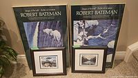 Two Robert Bateman gallery poster ads side-by-side with two smaller framed Group of Seven prints positioned below them on carpeted floor.