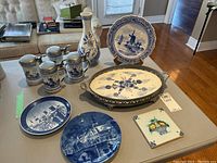 Full view of all items including steins, vase, plates, tray, and tile on table