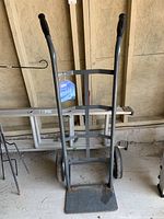 Front view of Ultra Steel twin handle hand truck showing metal frame, dual handles with black rubber grips, and flat loading plate.