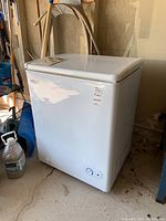 White Danby Millenium chest freezer viewed from an angle in a garage setting.
