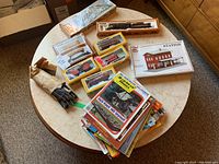 Overview of vintage model trains, tracks, and magazines on table.
