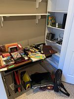 Wide shot of table and shelves showing assortment of briefcases, office supplies, folders, and electronics