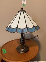 Full view of the stained glass lamp on a wooden table, showing the full shade and metal base.