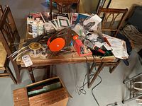 Photo of stained glass supplies arranged on a wooden table showing tools, solder wire, flux bottles, and pattern booklets.