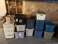 Stacked storage bins and three drawer storage cart in basement setting.