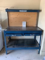 Full front view of Mastercraft metal workbench showing pegboard back, two drawers, and bottom shelf.
