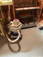 Photo showing Black & Decker WorkMate Deluxe work table and ShopVac wet/dry vacuum in basement corner.