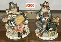 Pair of bisque porcelain musician figurines on a wooden surface, showing full figures and details